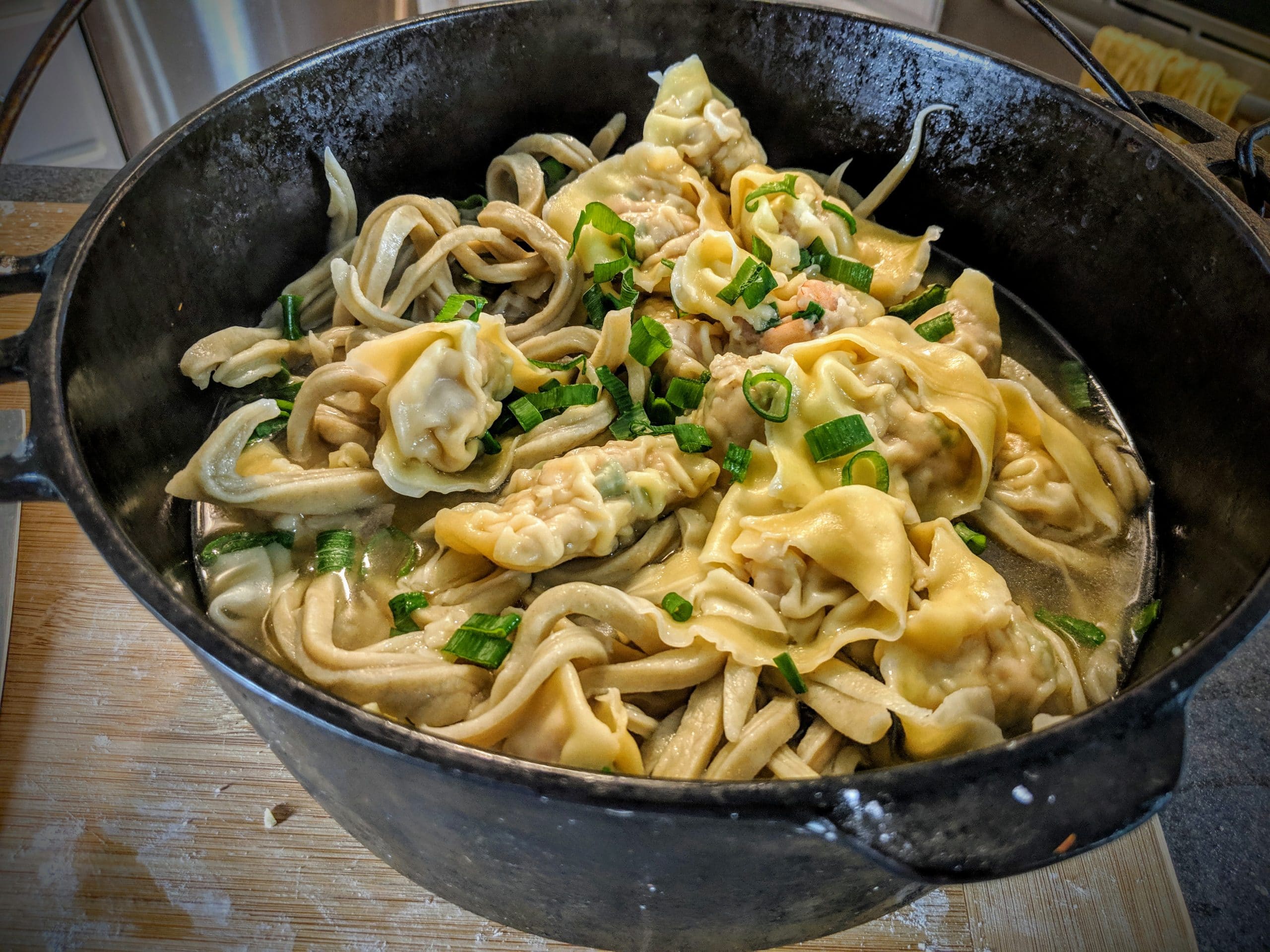 A cast iron pot filled with wonton egg noodle soup