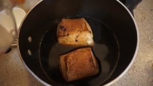 Chashu pork belly being braised in a pot